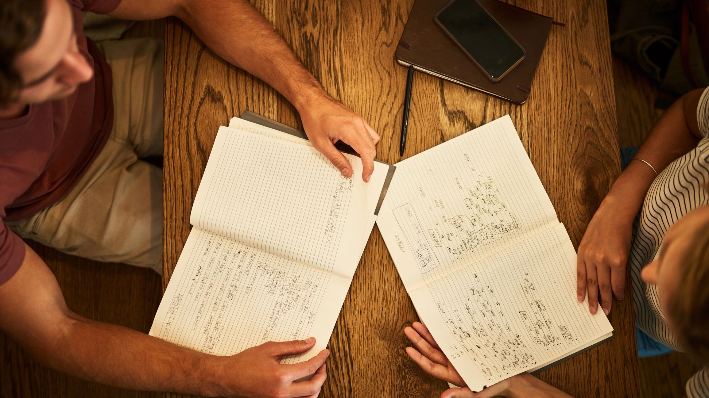 Two students comparing notes at a cafe table